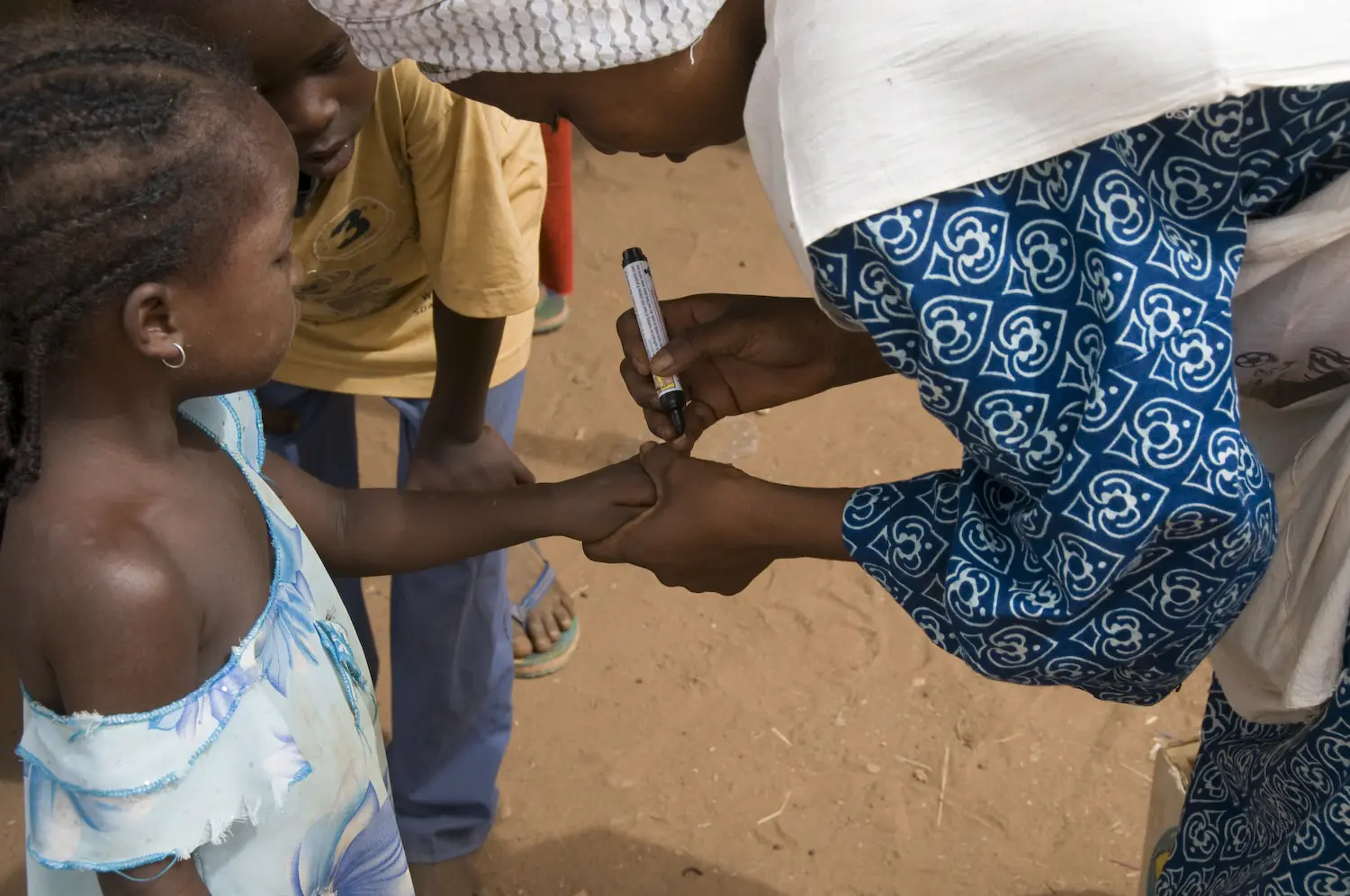 Health worker in Niger administering polio vaccine to child