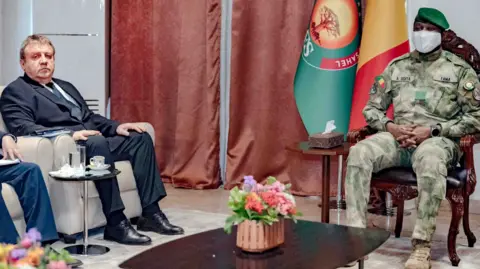 Russia’s Ambassador to Mali, Igor Gromyko, seated on the left in a formal suit, and Mali’s coup leader Colonel Assimi Goïta on the right dressed in military camouflage.