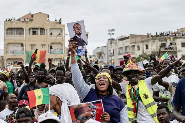 A supporter of Senegalese Prime Minister Ousmane Sonko dances holding his portrait during a rally in Dakar on November 8, 2025